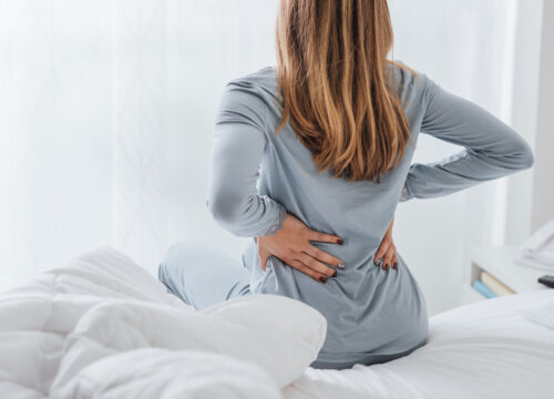 Photo of a woman with some mild back pain, getting up out of bed